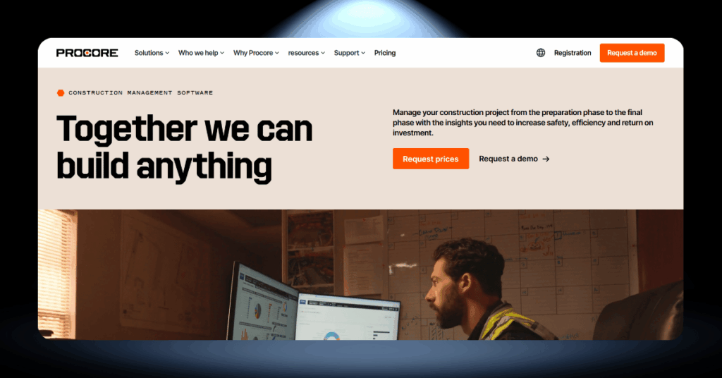 Procore construction management software page showing a site worker reviewing project dashboards on a desktop monitor